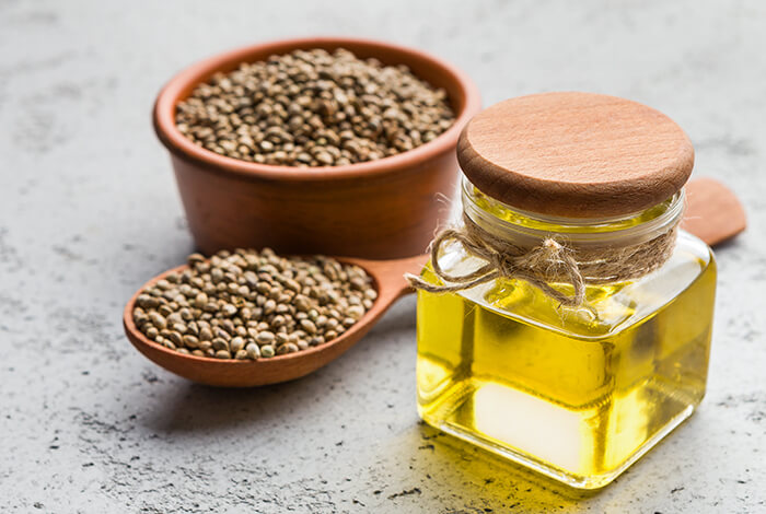 A jar of hemp oil, a bowl of hemp seed, and a spoon full of hemp seed.