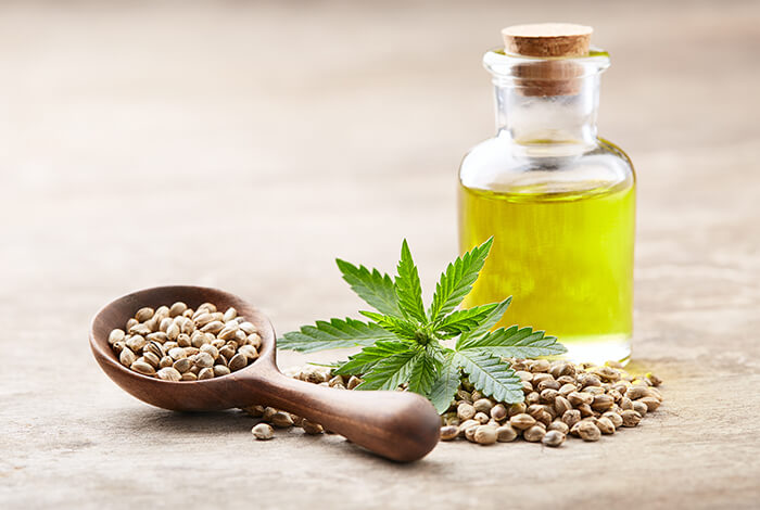 A vial of hemp oil and a spoonful of hemp seeds.