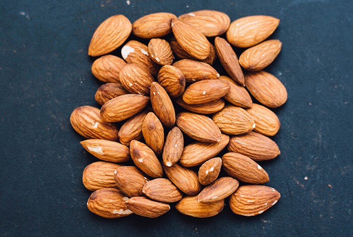 Almonds on top of a blue-colored surface.