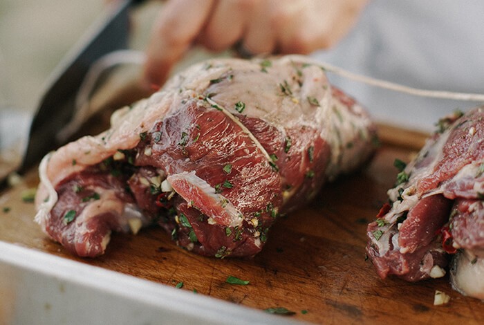 Two pieces of seasoned bison meat on a wooden chopping board.