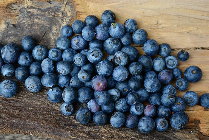 A handful of blueberries on a wooden surface.