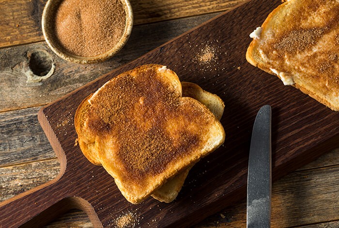 Slices of cinnamon toast on a wooden chopping board.