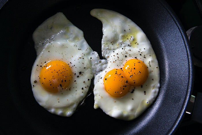 Three seasoned fried eggs in a pan.