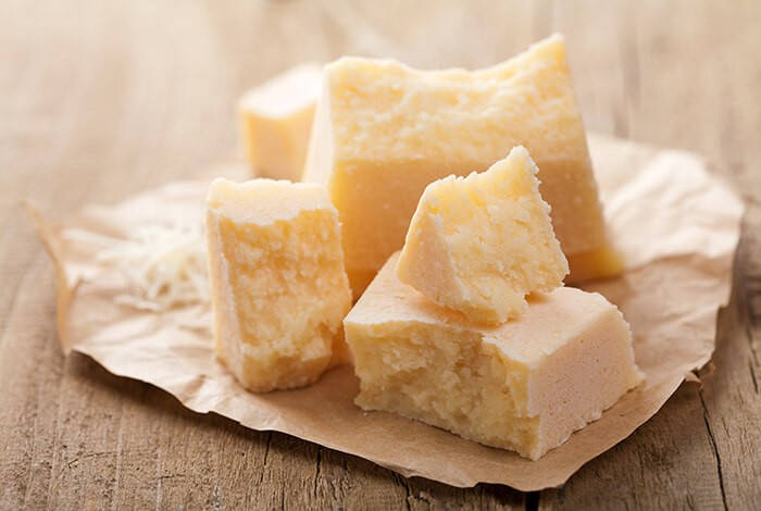 Pieces of parmesan cheese on a wooden surface.