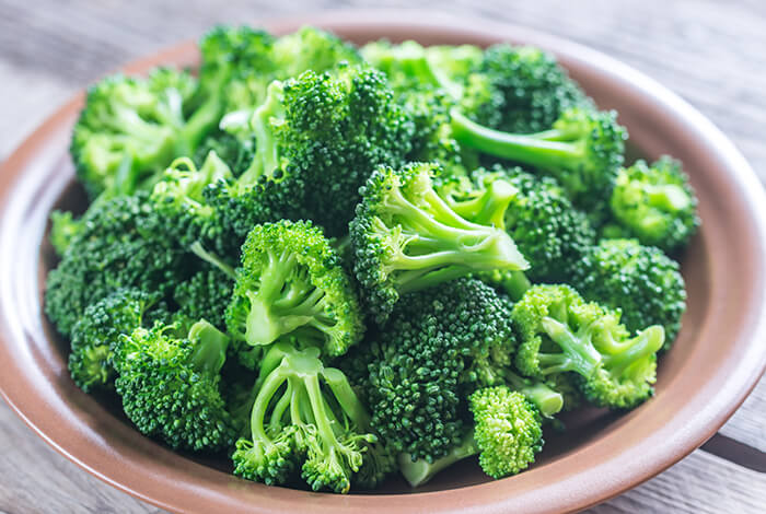 Pieces of raw broccoli for dogs placed on a clay plate.