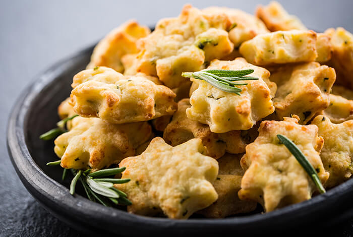 Homemade cheesy dog treats placed in a wooden bowl.