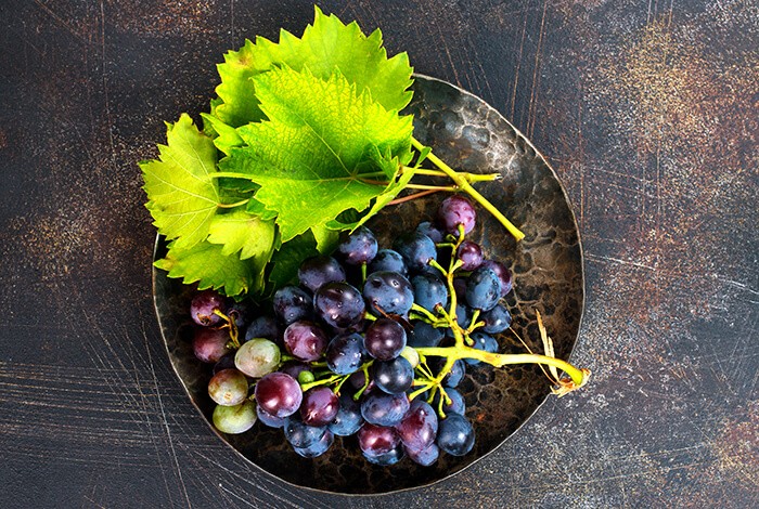 A bunch of grapes placed on a dark metal plate.