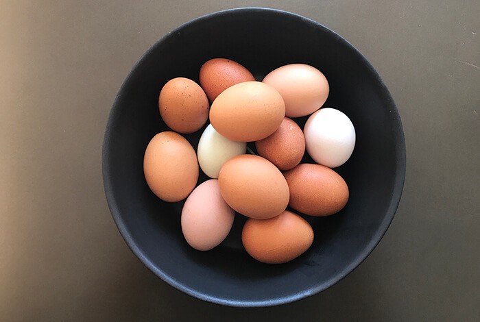 Different types of eggs filling up a blue bowl.