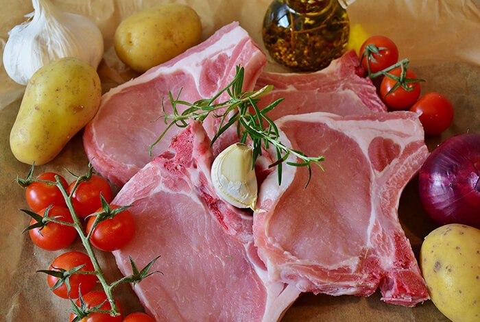 Porkchops surrounded by vegetable ingredients. 