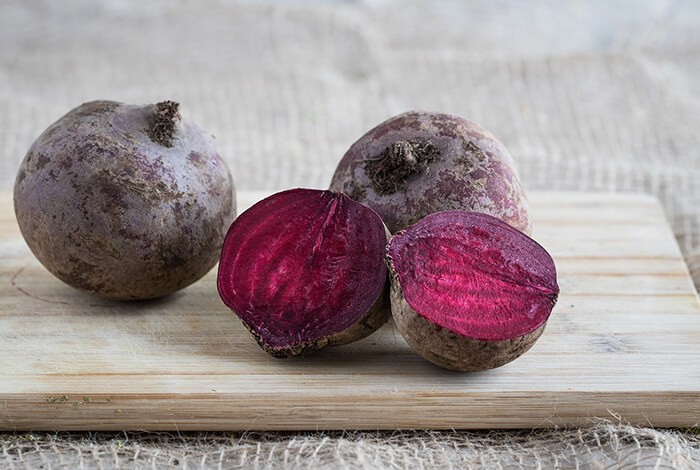 Beets on top of a wooden chopping board. 