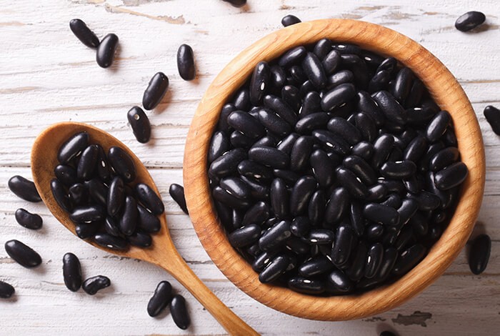 A bowl filled with raw black beans.