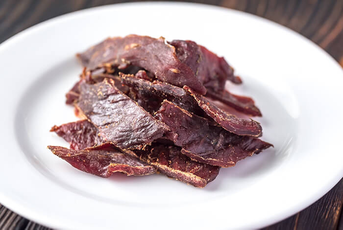 Beef jerky for dogs placed on a ceramic plate.