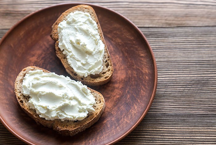 Cream cheese generously spread on top of toasted bread.