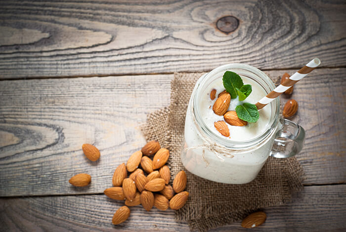 A handful of almonds and an almond yogurt smoothie in a mason jar.