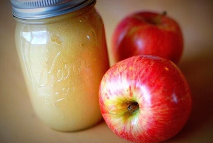 A bottle of applesauce and two apples.