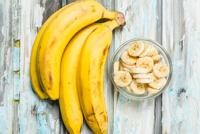 A bowl of sliced bananas and some banana pieces.