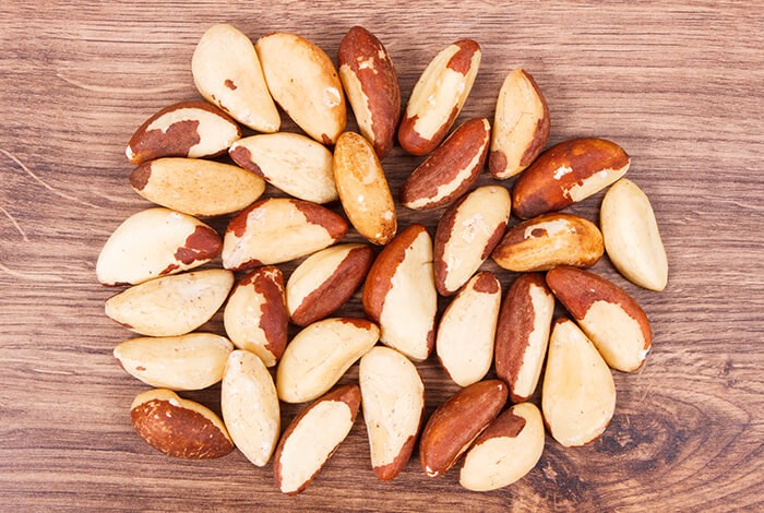 Brazil nuts spread across a wooden surface.