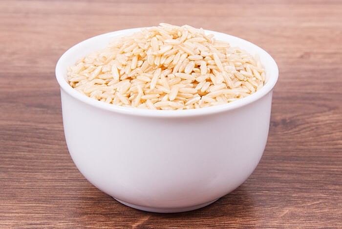 A bowl filled with uncooked brown rice.
