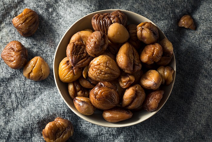 A bowl of chestnuts on a cloth surface.