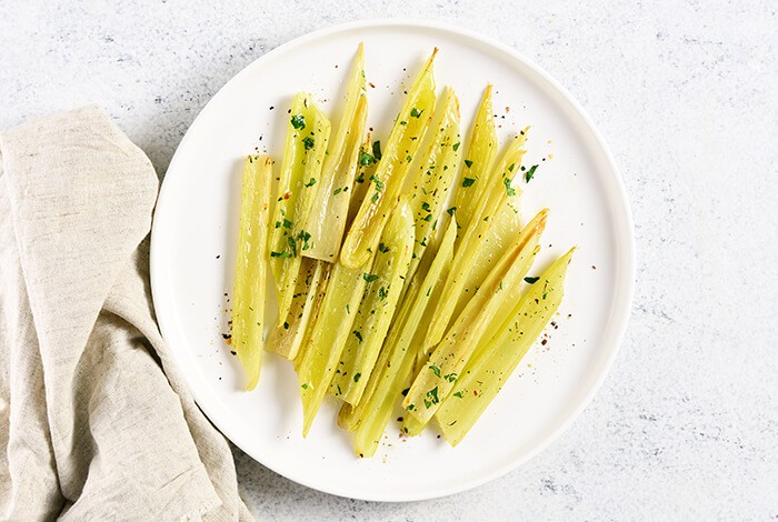 Cooked celery stalks on a white plate. 