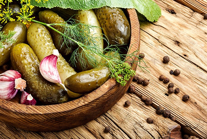 Pickled cucumbers with red onions and dill in a wooden bowl.