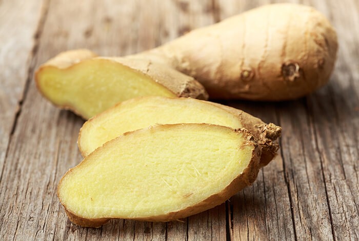 Pieces of sliced ginger on a wooden surface.