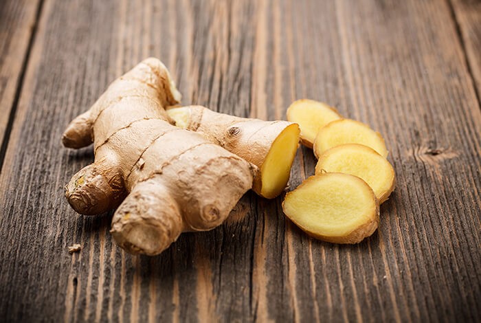 Ginger slices placed on top of a wooden surface. 