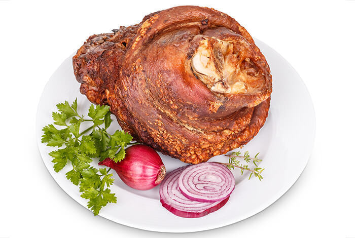 Cooked ham with red onions on a white plate.