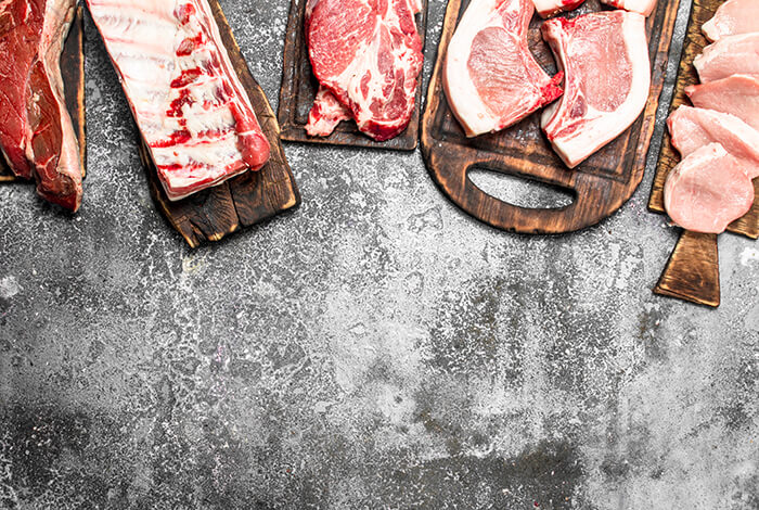 A variety of meats placed on wooden chopping boards.