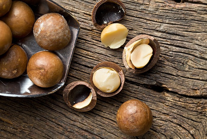 Macadamia nuts spread across a wooden surface.