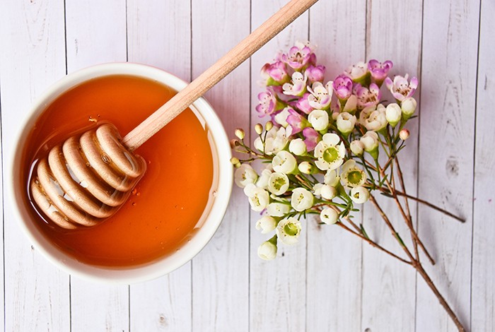 A bowl filled with manuka honey and a honey dipper.