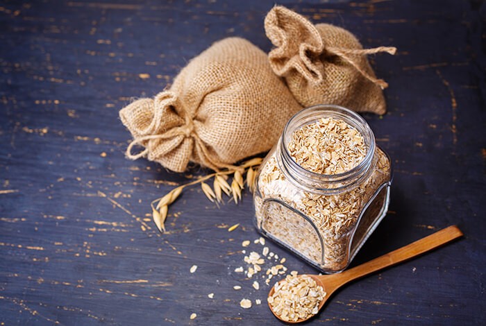 A jar of raw oatmeal next to two burlap sacks. 