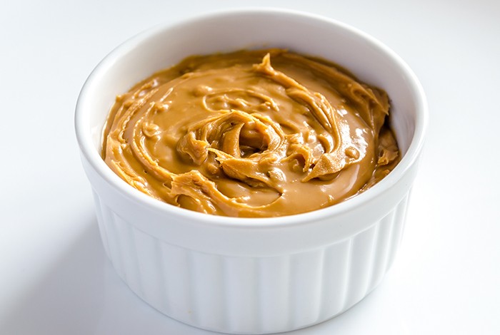 A bowl filled with honey peanut butter. 