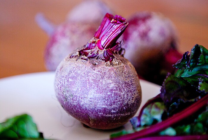 A raw beet on a ceramic plate.
