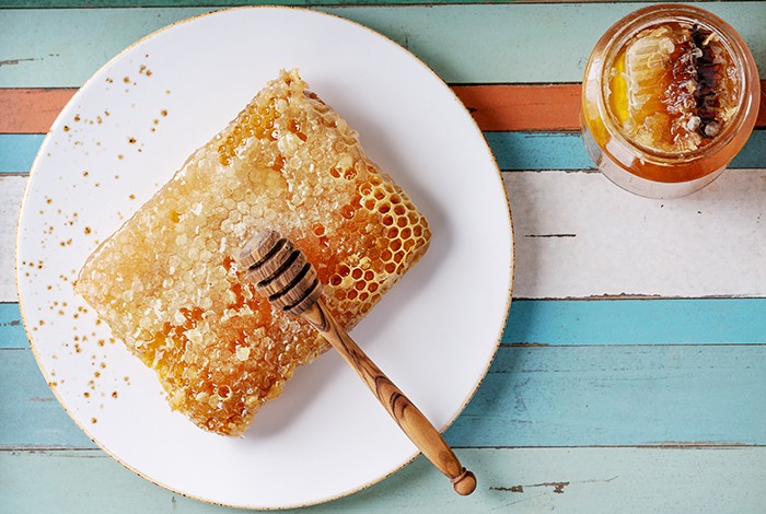 A honeycomb on a glass plate and a jar of honey with honeycomb.