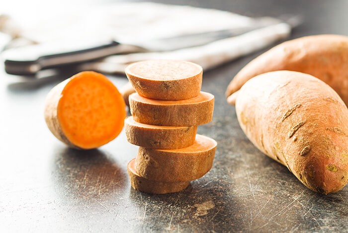 Cut raw sweet potatoes displayed on a smooth surface.