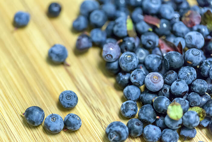 A bunch of blueberries on top of a wooden surface.