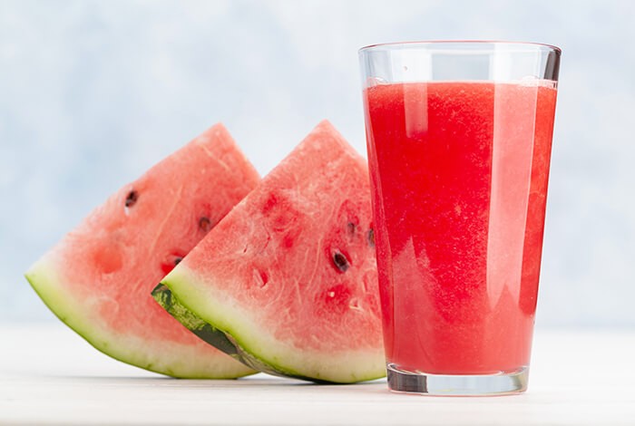 Two slices of watermelon and a glass of watermelon juice.