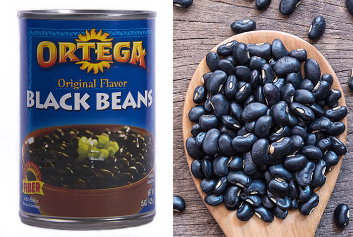 A can of black beans opposite a wooden spoon filled with raw black beans.