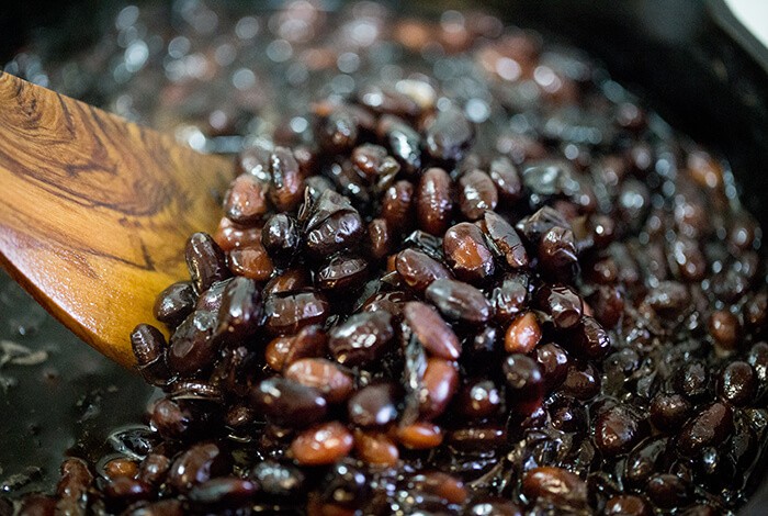 Black beans being cooked in a pan.