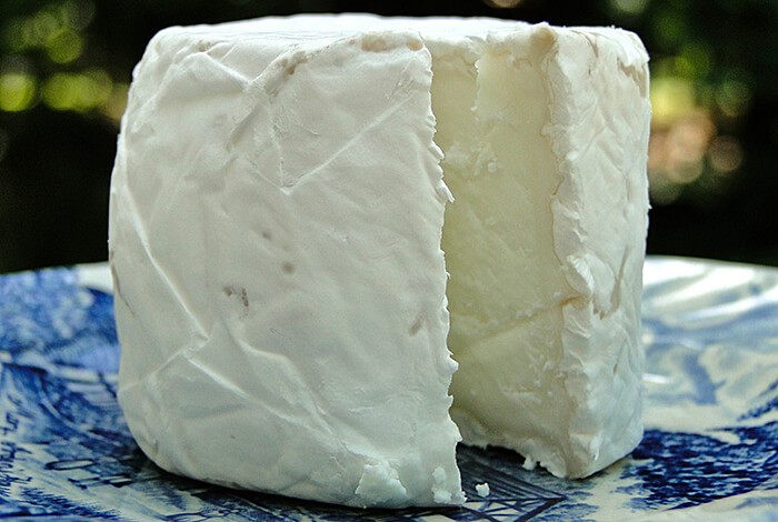 A block of goat's cheese on a blue ceramic plate.