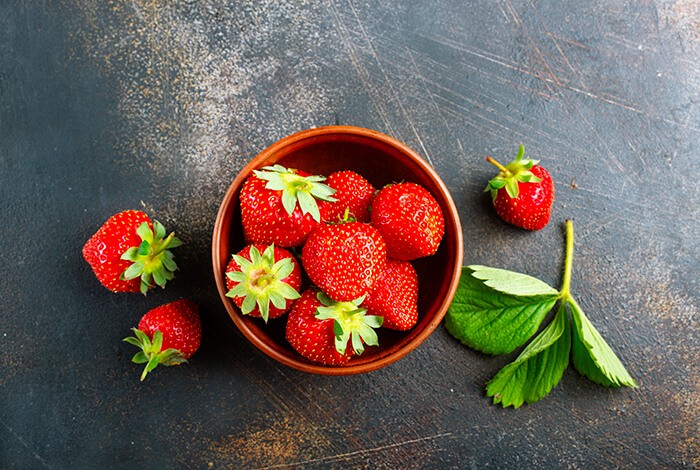 Two white ceramic bowls filled with strawberries. 