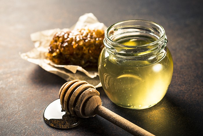 A small glass jar filled with clear honey. 