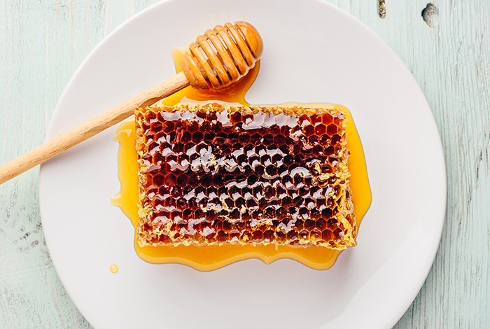 A honeycomb with honey placed on a ceramic plate. 