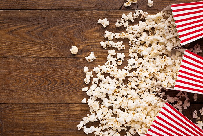 3 buckets of popcorn splayed on a wooden surface. 