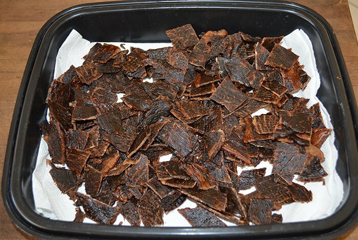 Beef jerky for dogs placed in a black square bowl.