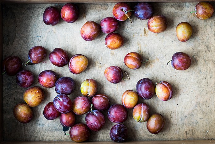 Fresh plums placed in a wooden box.
