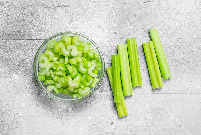 A glass bowl of sliced celery stalks.