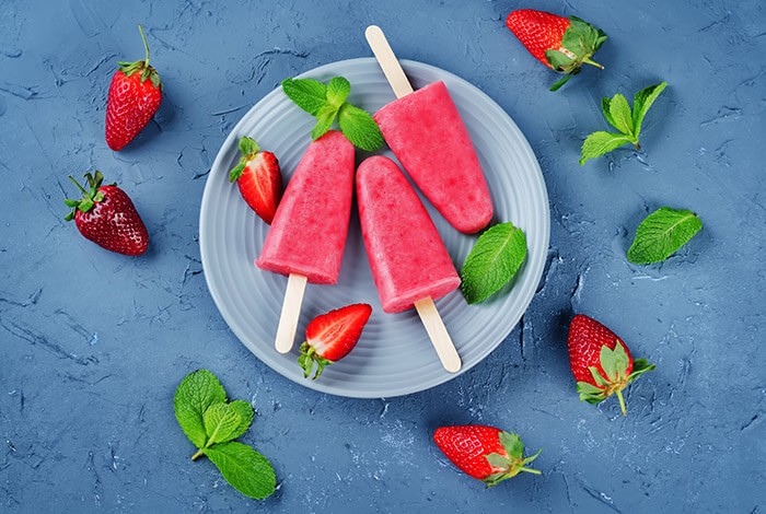 Strawberry ice pops and strawberries placed on a plate.