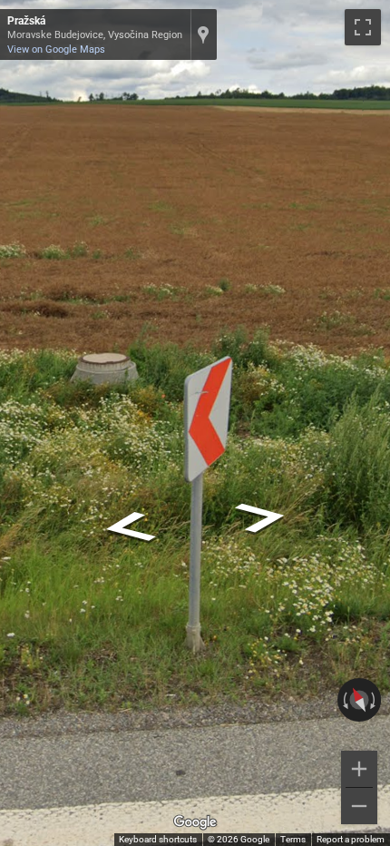 Czech road chevron sign showing a red arrow on a white background, indicating a road feature.
